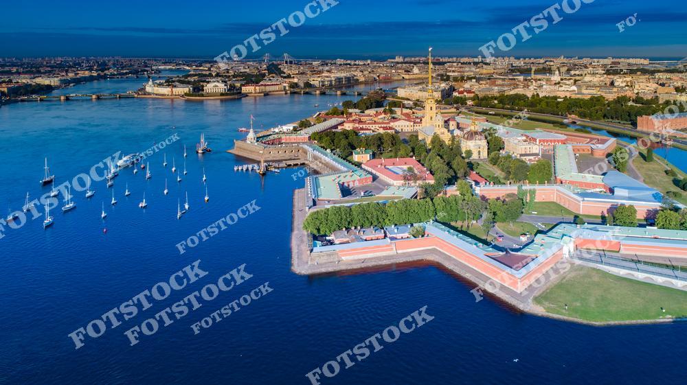 Фотография панорамного вида Санкт-Петербург, Россия, выполненная с дрона. На фото изображён исторический центр города: Петропавловская крепость, расположенная на Заячий остров, акватория реки Нева, а также Васильевский остров. Фотоснимок передаёт масштаб города, его мосты и каналы, характерную планировку и архитектуру центральной части Санкт-Петербурга. Это изображение отражает уникальный облик северной столицы и её туристическую привлекательность для путешествий по России.